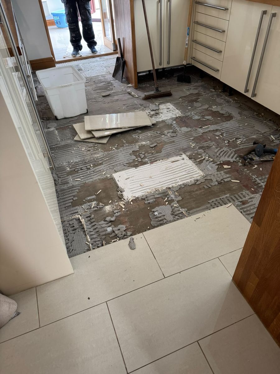 Kitchen floor stripped back to subfloor with old tile adhesive, ready for new flooring