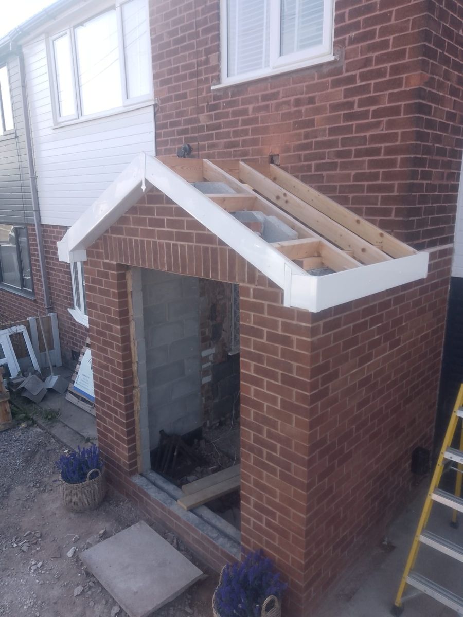 Brick porch mid-build with timber roof frame exposed, before tiling